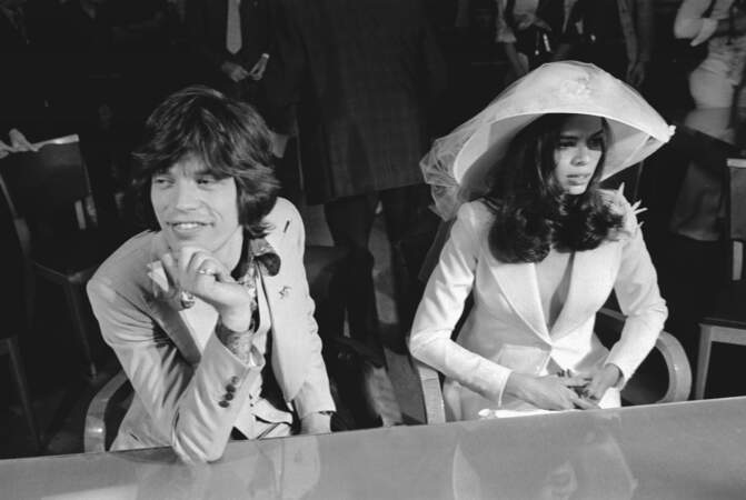 A Saint-Tropez, dans une salle de la mairie, Mick Jagger, en costume, assis aux côtés de Bianca Perez Morena de Macias, portant une capeline en 1971
